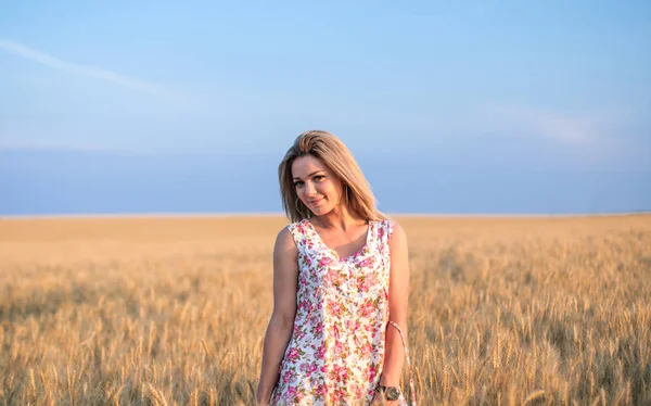 Joven seductora rural rubio cabello mujer en vestido en el campo de trigo amarillo en la puesta del sol — Foto de Stock