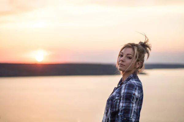 Young seductive rural blond hair woman in plaid shirt, orange sunset and lake on the background — Stock Photo, Image