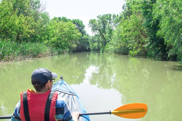 Man is paddling on kayak on the river duct, green forest around — Stock Photo, Image