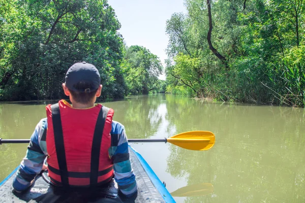 Man is paddling on kayak on the river duct, green forest around — Stock Photo, Image