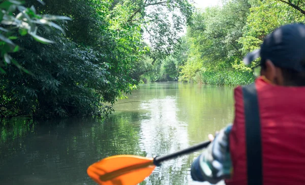 Mann paddelt mit Kajak auf dem Fluss, grüner Wald umringt — Stockfoto