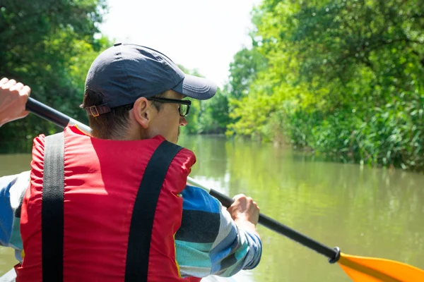 Hombre está remando en kayak en el conducto del río, bosque verde alrededor — Foto de Stock