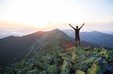 kafkas adam yürüyüşçü havada elleri ile gün batımını izlerken yeşil taşların zirvesinde dağ