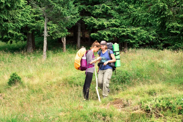 Deux randonneuses sur le sentier forestier dans les montagnes à la recherche d'un moyen sur la carte — Photo