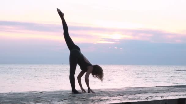 成熟的女人与美丽的身体做瑜伽分裂在日出在海上 瑜伽姿势的剪影 — 图库视频影像