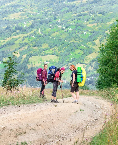 Három fiatal női túrázók a hegyi ösvényen, dombon a háttérben — Stock Fotó