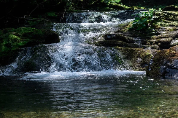 Malý horský vodopád s čistou vodou, která protéká rybníkem — Stock fotografie