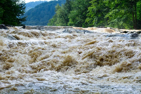 fast stream of dirty water in river rapids and waterfall