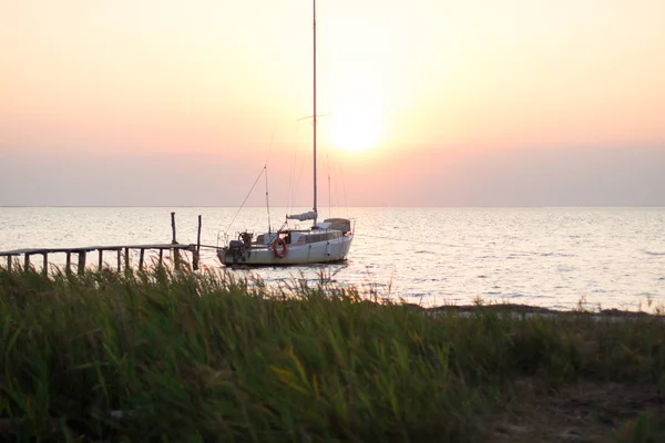 Yacht amarré à quai à l'heure du coucher du soleil, soleil couchant sur le fond — Photo