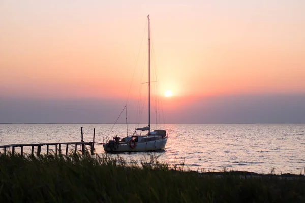 Яхта пришвартована на причале на закате, солнце заката на заднем плане — стоковое фото