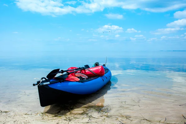 Kayak bleu au bord de la mer, eau bleue lisse et ciel — Photo
