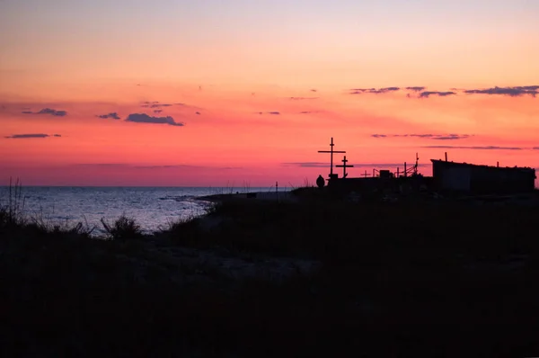 Οίκος των μοναχών και σταυρούς στην παραλία του νησιού, κόκκινο ηλιοβασίλεμα στη θάλασσα — Φωτογραφία Αρχείου