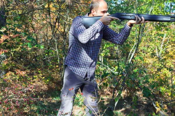 Macho con escopeta semiautomática en el bosque otoñal apuntando — Foto de Stock