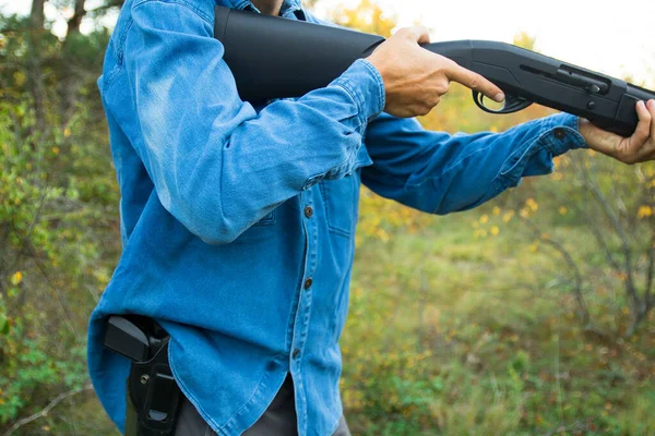 Man met semi-automatisch geweer en pistool in holster in het herfstbos gericht — Stockfoto