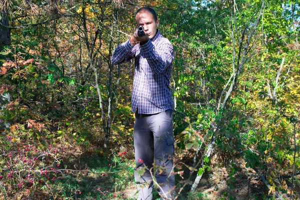 Samiec z półautomatyczną strzelbą w jesiennym lesie celuje ze strzelby — Zdjęcie stockowe