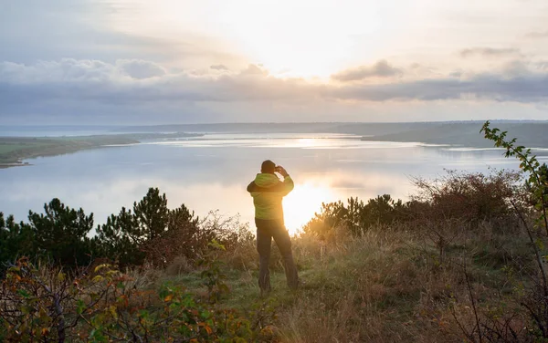 Homme prend une photo du lever du soleil sur le lac, beau paysage — Photo