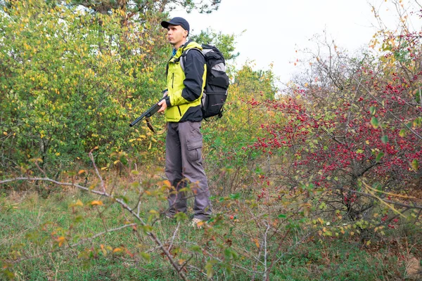 Mężczyzna z półautomatyczną strzelbą i plecakiem poluje w jesiennym lesie — Zdjęcie stockowe
