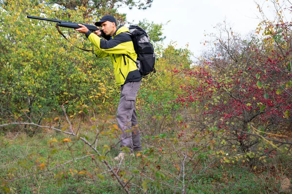 Hombre con escopeta semiautomática y mochila está cazando en el bosque de otoño — Foto de Stock
