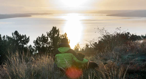 Man with his labrador dog admiring orange sunrise over the lake — ストック写真