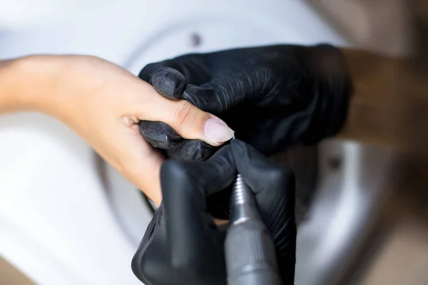 黒い手袋のマニキュア師はマニキュアドリル装置でマニキュアを作っています — ストック写真