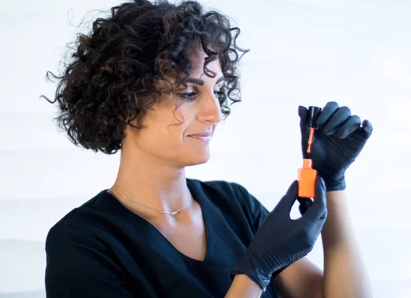 Maniküre Meister Schwarzen Handschuhen Hält Orangefarbenen Nagellack Auf Dem Weißen — Stockfoto