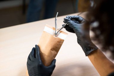 Manikür ustası manikür aletini sterilizasyon için kese kağıdına koydu.