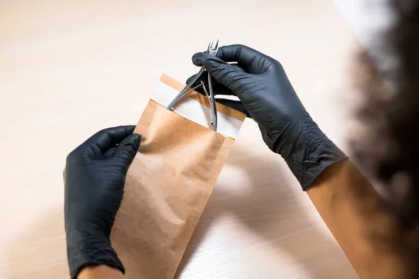 Manikür ustası manikür aletini sterilizasyon için kese kağıdına koydu.