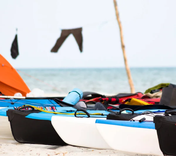 different color inflatable kayaks with equipment stay in a row on the wild beach in the camping at sunset light