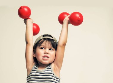 Çocuk beden eğitimi kırmızı dumbbells ile çalışmaktadır