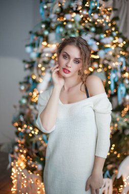 Kıvırcık saçlı güzel kız Noel ağacının yanında poz veriyor. 