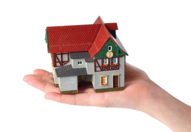 Beyaz bir arka plan üzerinde kadın ellerde eski bir evin plastik modeli