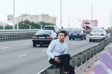 Adam yola yakın köprüde oturuyor