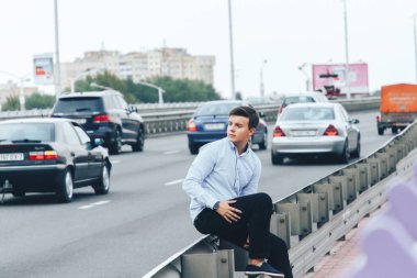 Adam yola yakın köprüde oturuyor