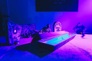October, 28-29, 2017 - Minsk, Belarus: Art space, Party dedicated to HALLOWEEN, young man sitting behind coffin in club