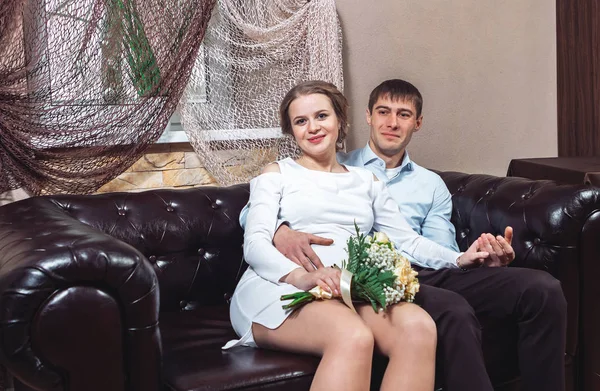 美丽的新娘和新郎的全家福肖像坐在皮革沙发上 — 图库照片