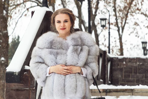 beautiful young woman in fox fur coat in winter