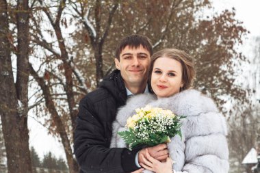 parkta kışın kucaklayan güzel düğün çifti