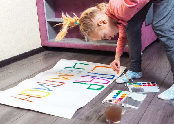 Young girl drawing placard on floor at home