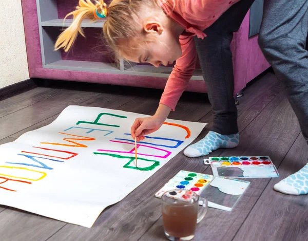 Young girl drawing placard on floor at home