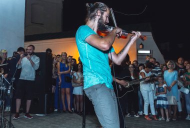 1 Eylül 2018 - Minsk, Beyaz Rusya: Sokak şenlikleri akşam şehirde. adam sokakta insanların önünde oynarken keman ile