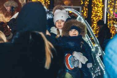 30 Aralık 2018 - Minsk, Beyaz Rusya: kasaba meydanında yeni yıl kutlamaları. Anne oğluyla parlayan arabada oturan