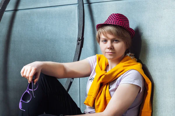 Chica con un sombrero rojo se sienta cerca de una pared — Foto de Stock