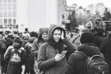 23 Şubat 2019 Minsk Belarus 23 Şubat'ta tatil onuruna yarış Kadın sokakta insanlar arasında bir adamın yanında telefona bakar