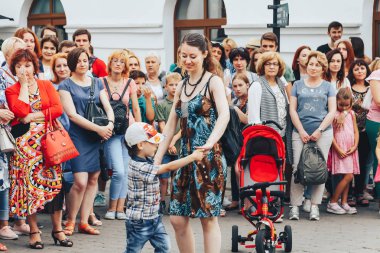 21 Temmuz 2018 , Minsk,Belarus Caddesi sokakta insanların önünde küçük bir çocukla dans eden kadın yürüyor