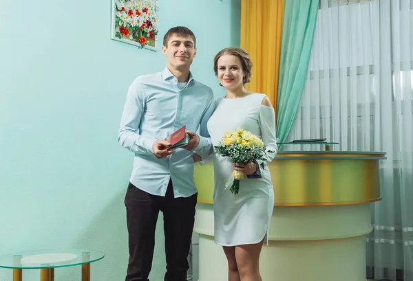 El novio en la camisa y la novia en un vestido blanco con documentos de matrimonio — Foto de Stock