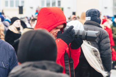 23 Şubat 2019 Minsk Belarus 23 Şubat'ta tatil onuruna yarış bir fotoğrafçı kırmızı ceketli bir kamera ile insanlar arasında duruyor