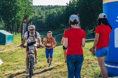 26-27 Mayıs 2018 Naliboki,Belarus Tüm Belarus amatör maratonu Naliboki Aa adam bisiklete biniyor ve bir adam finişte koşuyor