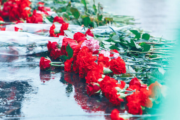 Красные розы лежат на черном граните
