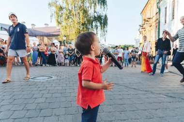 4 Ağustos 2018 Akşam kentte sokak şenlikleri Mikrofonlu küçük bir çocuk bir sokak konserinde meydanda duruyor