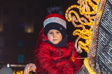 30 Aralık 2018 Minsk Belarus Yeni Yıl kutlamaları şehir meydanında. Küçük bir çocuk yeni yıl tatili sırasında gezinen insanlar arasında meydanda parlayan bir at üzerinde oturur